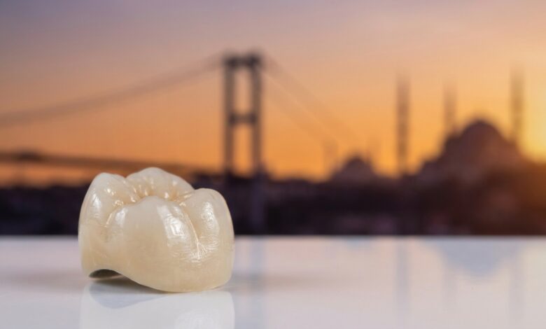 Gros plan d'une couronne dentaire en céramique d'un blanc naturel, nette et parfaite, avec en arrière-plan une vue panoramique floue et ensoleillée d'Istanbul et du pont du Bosphore au coucher du soleil.
