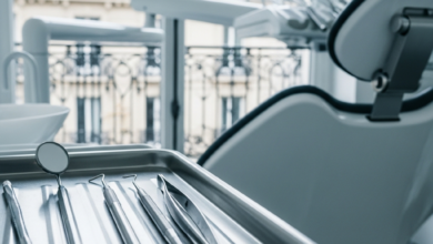 Close-up of sterile dental instruments on a tray in a modern, clean dental clinic. In the soft-focus background, through a window, classic French architecture is visible under bright, natural light.