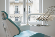 A photorealistic, highly detailed image of a modern, empty dental chair in a clean, brightly lit clinic. Sleek, advanced dental instruments are neatly arranged on a tray beside the chair. Through a blurred window in the background, classic Parisian architecture is visible, suggesting a serene and professional dental experience in France.