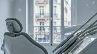 A sharp, detailed close-up of modern dental equipment, possibly a polished dental instrument or part of a dental chair, within a bright, clean, and contemporary dental treatment room. In the soft-focus background, a blurred window reveals a hint of classic French architecture, such as a traditional Parisian building facade, under subtle, professional lighting. The scene suggests advanced healthcare and a structured environment, with no visible text or branding.