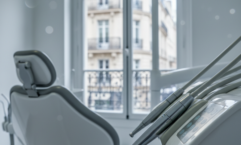 A sharp, detailed close-up of modern dental equipment, possibly a polished dental instrument or part of a dental chair, within a bright, clean, and contemporary dental treatment room. In the soft-focus background, a blurred window reveals a hint of classic French architecture, such as a traditional Parisian building facade, under subtle, professional lighting. The scene suggests advanced healthcare and a structured environment, with no visible text or branding.