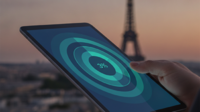 Close-up of a hand holding a digital tablet displaying abstract, overlapping layers of financial coverage in blues and greens. In the blurred background, the iconic silhouette of the Eiffel Tower rises above Parisian rooftops under a soft sky, signifying France's healthcare system.